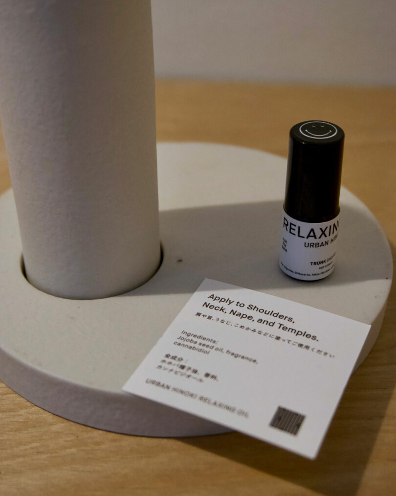 A bottle labeled "RELAXING" sits on a white surface next to an instruction card, capturing the chic vibe of TRUNK(HOTEL) CAT STREET with its stylish design and thoughtful ingredients list.
